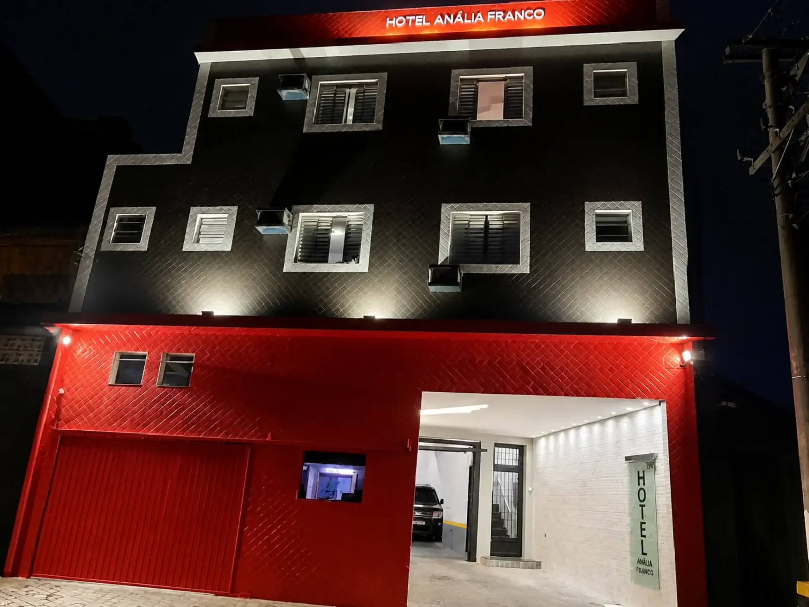 Fachada iluminada em vermelho e grafite do Hotel Anália Franco à noite